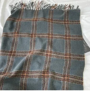 Detailed view of the thick warm winter plaid scarf with elegant fringes and classic grey grid.
