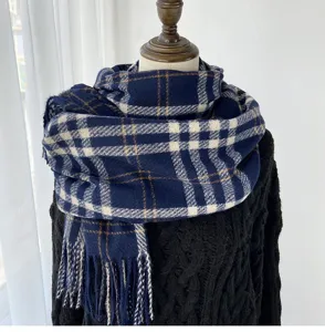 Detailed view of the soft blue and white plaid cashmere-feel scarf with fringe. Cozy winter accessory.