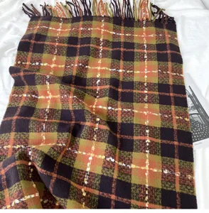Close-up detail of warm autumn winter plaid scarf featuring soft fringe and cozy texture.