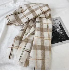 Detail view of a cozy plaid winter scarf draped neatly on a soft white fabric surface.