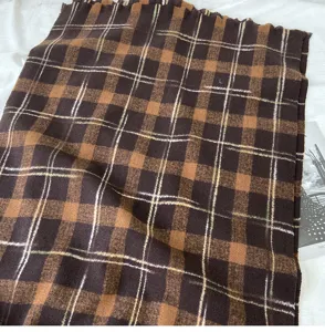 Detailed close-up of a retro brown plaid winter warm cozy thick scarf shawl accessory.