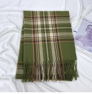 Close-up of green plaid cashmere-feel scarf with fringe tassels detail in cozy winter scene.