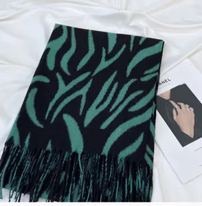 Close-up detail shot of green and black striped tassel faux cashmere winter scarf.