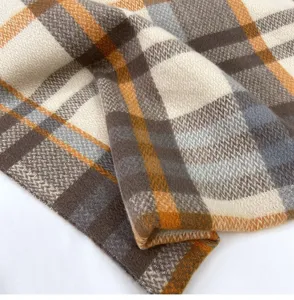 Close-up detail of soft autumn winter plaid scarf, cozy cashmere-feel patterned fabric.
