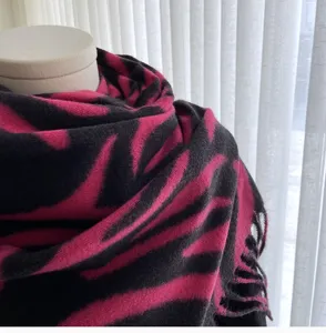 Detailed view of women's pink and black striped tassel cashmere-feel scarf winter wrap.