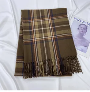 Brown plaid cashmere-feel winter scarf detail view with fringe and decorative prop magazine.