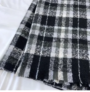 Close-up detail of soft black and white plaid winter scarf showing soft fabric texture.