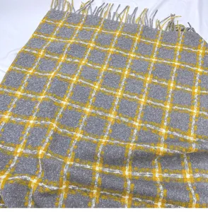 Close-up detail of grey yellow plaid winter warm cashmere-like scarf shawl tassel texture