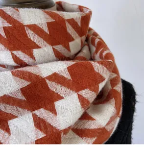 Close-up detail showing the soft texture and large orange-white houndstooth pattern scarf.