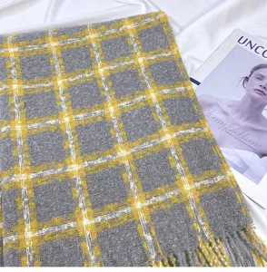 Close-up detail of the cozy grey and yellow plaid scarf with soft tassels and warm fabric.