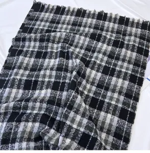 Detailed view of the black and white plaid winter scarf featuring a cozy fringe design.