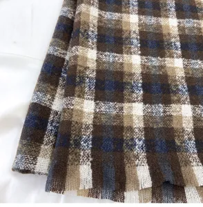 Close-up detail of soft winter plaid scarf fabric with brown, blue and white pattern texture.