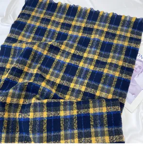 Detail view of a cozy blue and yellow plaid winter scarf with fringe, soft textured fabric.