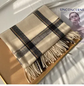 Detailed view of a classic plaid cashmere-feel tassel scarf in beige with black pattern.