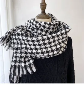 Detailed close-up of classic black and white houndstooth winter warm tassel scarf texture.