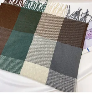 Close-up detail of the multi-color block check scarf featuring elegant fringe trim and soft texture.
