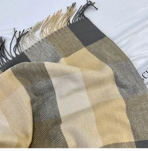 Close-up detail of the classic plaid winter scarf texture, soft cashmere feel fringe edge.