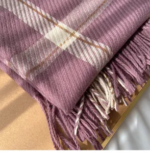 Detailed close-up view of a purple plaid winter scarf with fringed edges and soft warm texture.