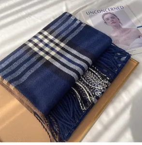 Detailed view of a cozy blue and black plaid winter scarf with elegant fringe trim texture.
