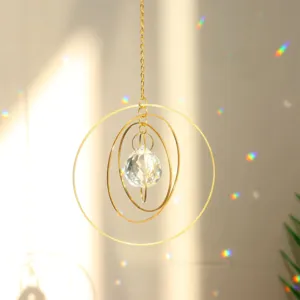 Faceted crystal suncatcher pendant with golden concentric rings casting rainbow light.