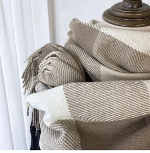 Detailed view of women's cozy beige and white plaid winter fringe scarf showcasing soft texture.