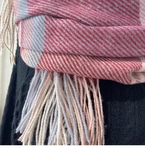 Close-up detail of soft tartan patterned scarf featuring elegant fringe and tassel design.