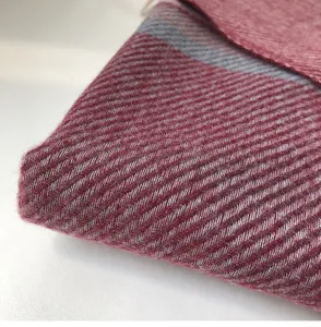 Close-up detail of soft winter cashmere-feel scarf showcasing red and grey twill texture.