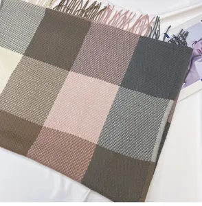 Close-up of a cozy multi-color plaid winter scarf with delicate fringes and soft texture.