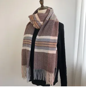 Detail view of cozy winter plaid scarf with fringe on mannequin, soft warm texture display.