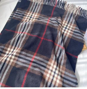 Detail of the classic British plaid scarf with black, camel, white and red lines with fringe.