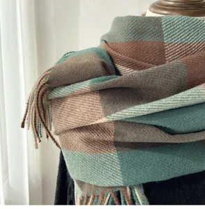 Close-up detail of vintage green and brown plaid blanket scarf with cozy fringe edges.