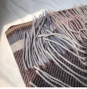 Detailed shot of a cozy winter plaid tassel scarf with soft cashmere-feel fabric.