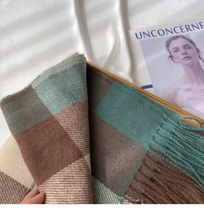 Close-up of cozy large plaid imitation cashmere scarf with retro fringe and green brown tones.