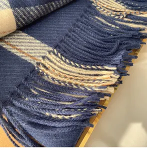 Close-up detail of soft blue plaid winter scarf with delicate fringes texture and warmth.