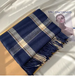 Close-up detail of dark blue plaid imitation cashmere scarf with soft tassel fringe.