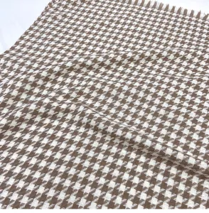 Close-up detail of a brown and white houndstooth winter scarf texture with soft fringe.