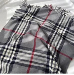 Detailed view of the grey plaid scarf showing soft cashmere-feel fabric and neat fringe.