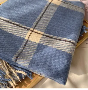 Close-up detail of blue plaid cashmere-feel scarf with fringe, soft winter accessory.