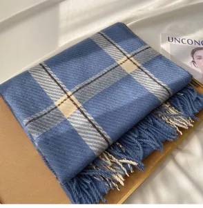 Blue plaid cashmere-like scarf detail showing soft texture and delicate fringe trim.