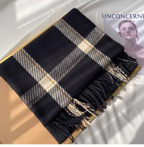 Detail view of the black plaid cashmere-feel winter scarf with soft fringe and classic pattern.