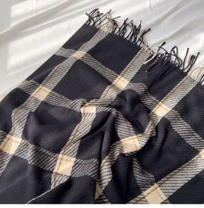Black and beige plaid scarf detail showing soft cashmere-like texture and neat fringe edges.