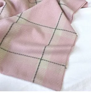 Close-up detail of soft pink plaid cashmere-feel scarf, textured winter warm fabric design.