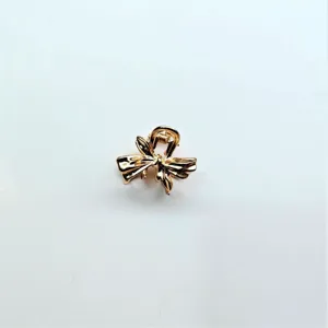 Golden metal bow mini hair claw clip detail, exquisite metallic hair accessory close up.