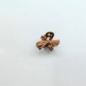 Detail shot of a matte brown bow hair claw clip, perfect for styling short or fringe hair.
