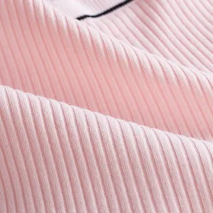 Détail de tissu en coton côtelé rose avec bordure rayée, texture douce et confortable.