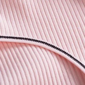 Gros plan de tissu en coton côtelé rose avec coutures contrastées noires pour sous-vêtements.