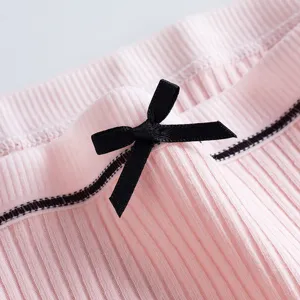 Vue détaillée de sous-vêtements côtelés roses pour femmes avec un joli nœud noir et bordure.