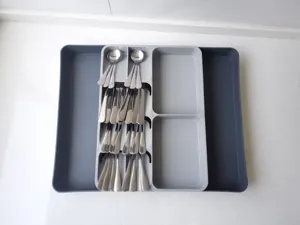 Vista detallada del organizador de cajón para cubiertos extensible gris con cucharas.