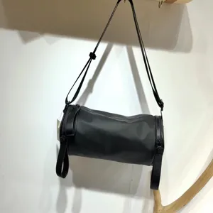 Detailed view of the black nylon cylindrical crossbody bag showing smooth zipper and strap.