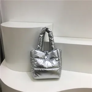 Détail de sac cabas matelassé métallique argenté, élégant sac à main en coton rembourré.